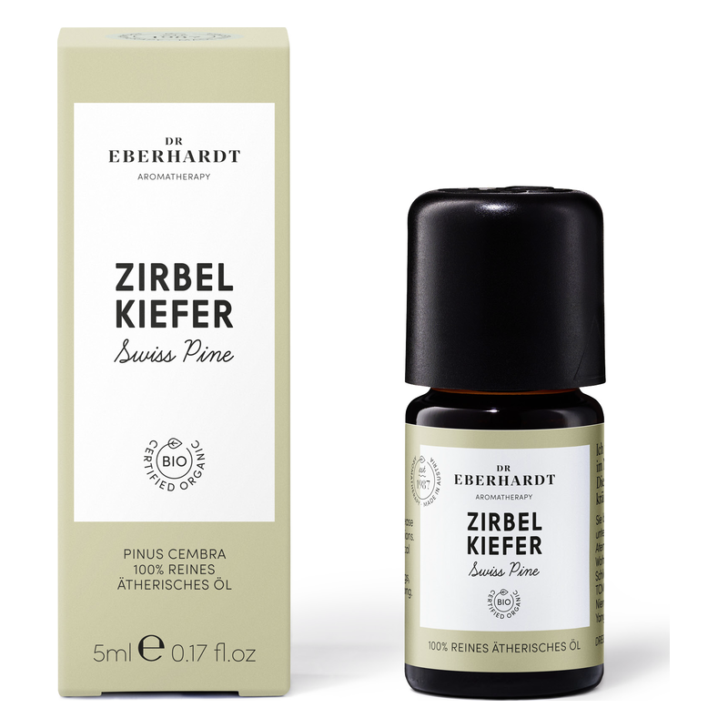 Flasche mit ätherischem Öl Zirbelkiefer in dunkler Verpackung neben einer hellen Schachtel mit grünen Akzenten.