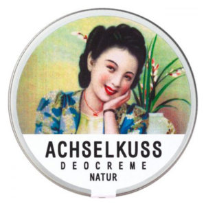 Runde Dose mit Deocreme, dekorativem Vintage-Motiv einer lächelnden Frau und der Aufschrift 'ACHSELKUSS DEOCREME NATUR'.