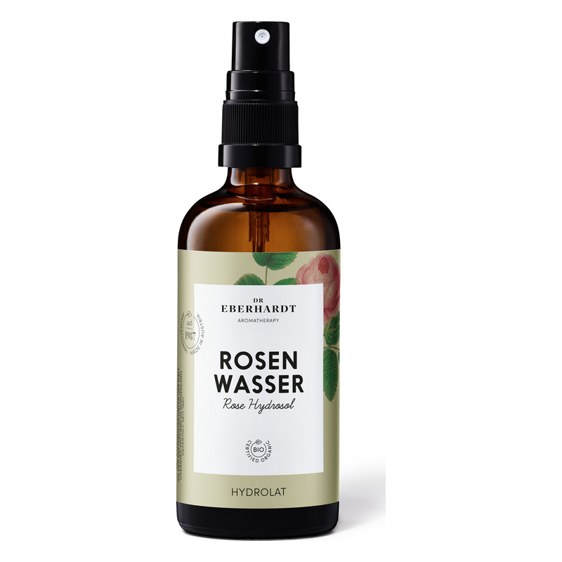 Braune Glasflasche mit Sprühkopf, etikettiert mit "Rosen Wasser" und botanischen Illustrationen.